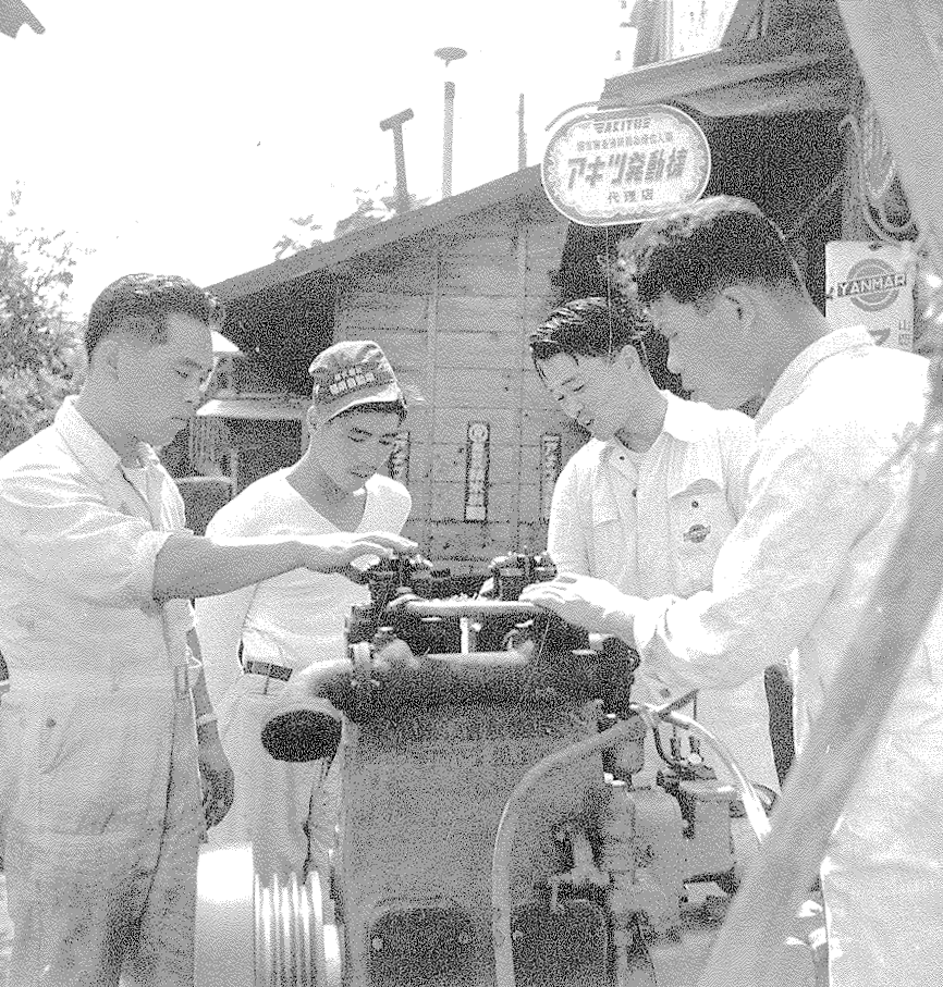 かつての福田機械店 発動機の前に立つスタッフ